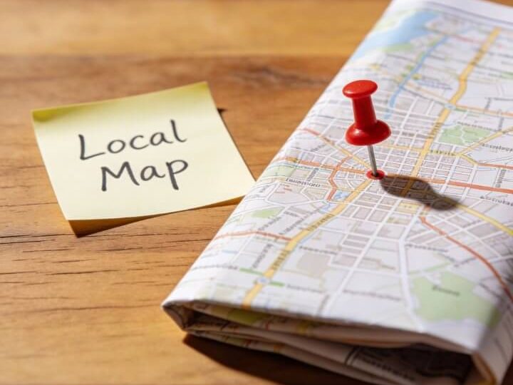 Local Map SEO: DigiAds44 Duisburg Gelbes "Local Map"-Post-it neben roter Stecknadel auf gefalteter Stadt-Karte auf Holztisch